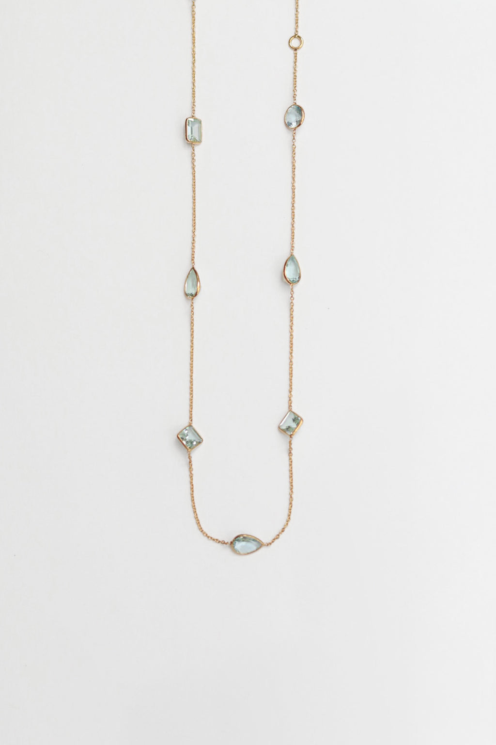 Delicate necklace with small aqua gemstones on a light gray background