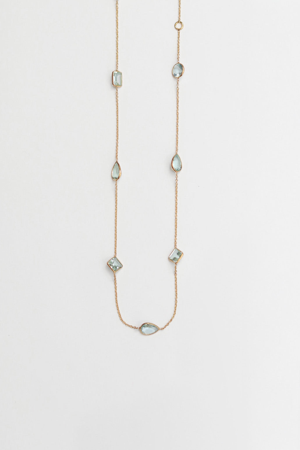 Delicate necklace with small aqua gemstones on a light gray background
