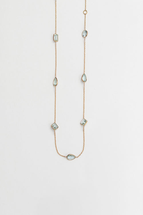 Delicate necklace with small aqua gemstones on a light gray background
