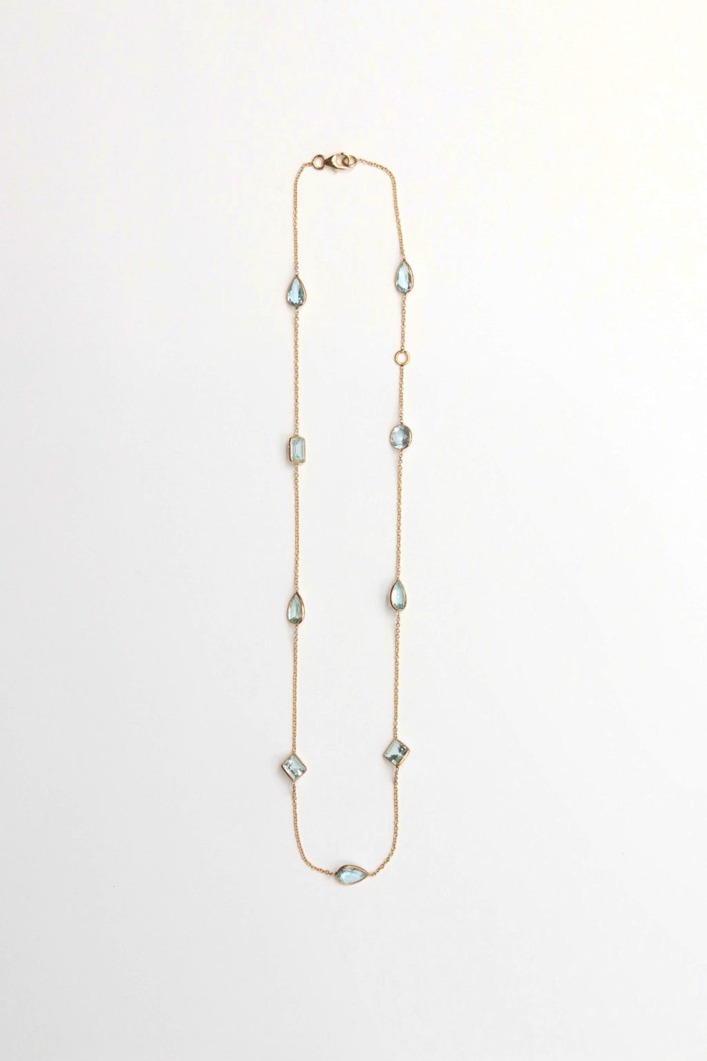 Long necklace with diamond and teardrop aqua gemstones on a white background