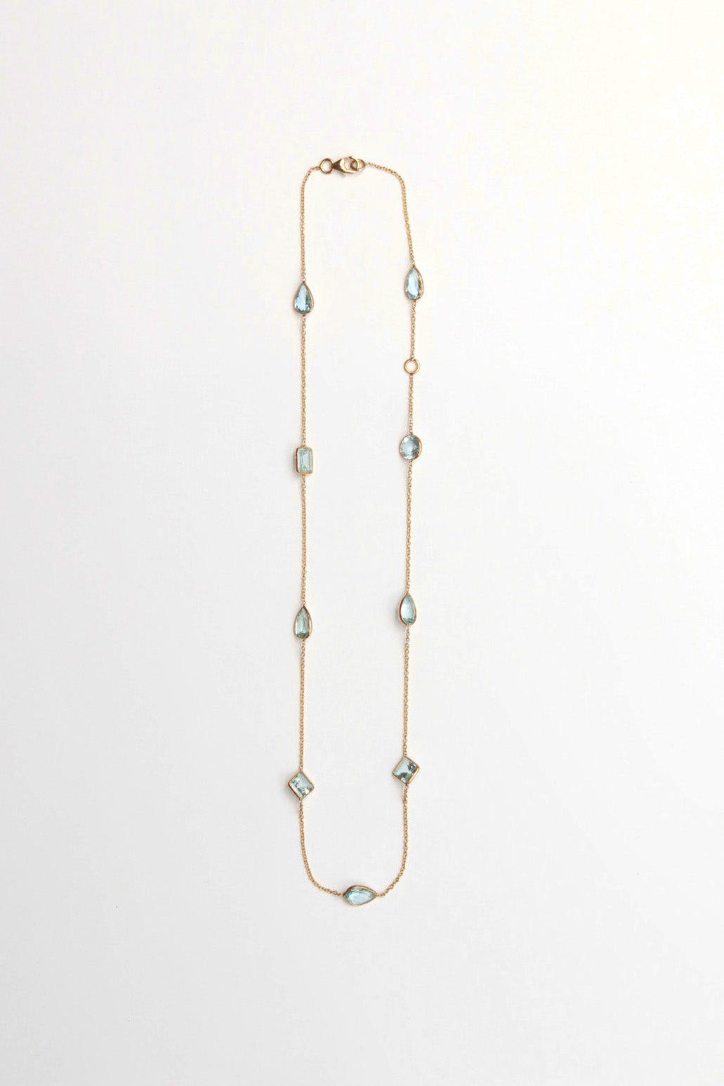 Long necklace with diamond and teardrop aqua gemstones on a white background
