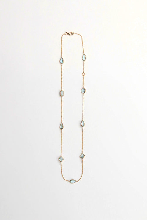 Long necklace with diamond and teardrop aqua gemstones on a white background