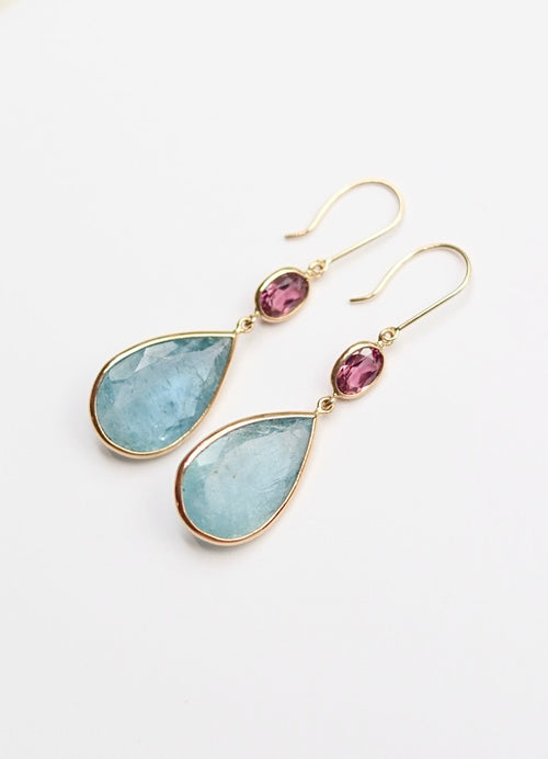 Gold earrings with teardrop-shaped gemstones on a white background