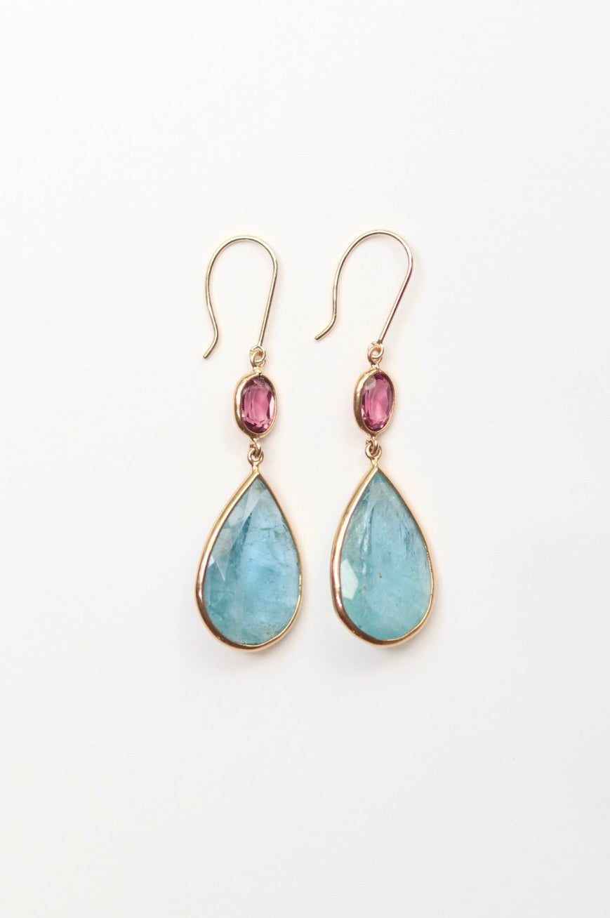 Teardrop-shaped earrings with pink gemstones on a white background
