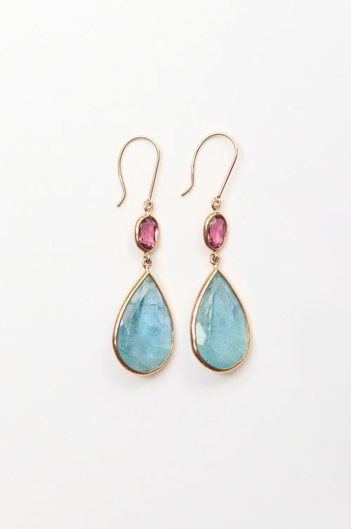 Teardrop-shaped earrings with pink gemstones on a white background