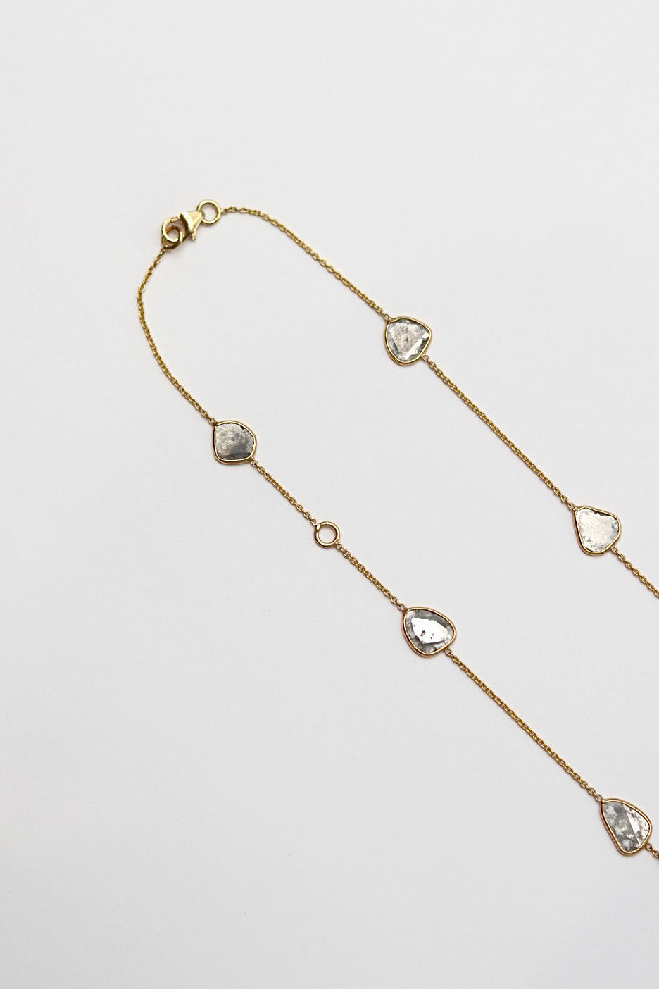 Gold necklace with diamond slice pendants on a light gray background