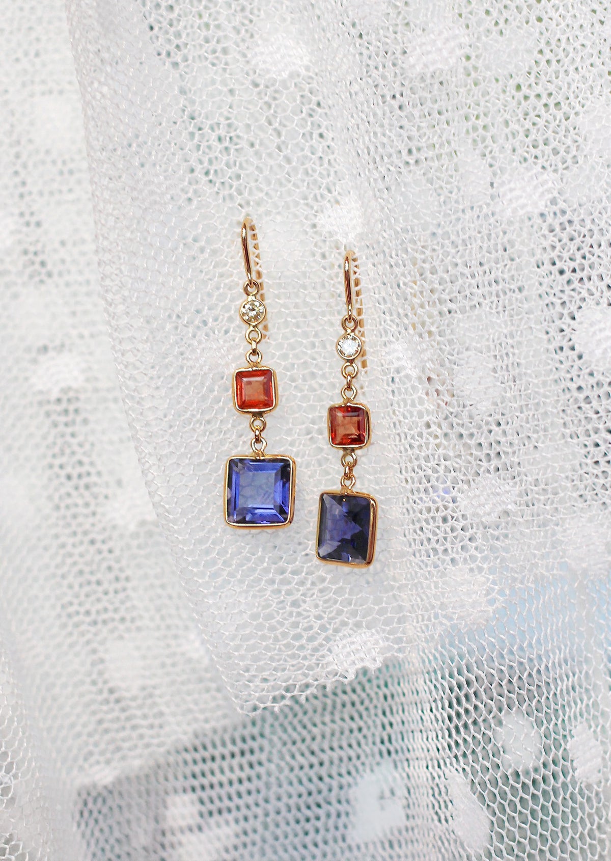 Pair of earrings with colorful gemstones on a textured white background