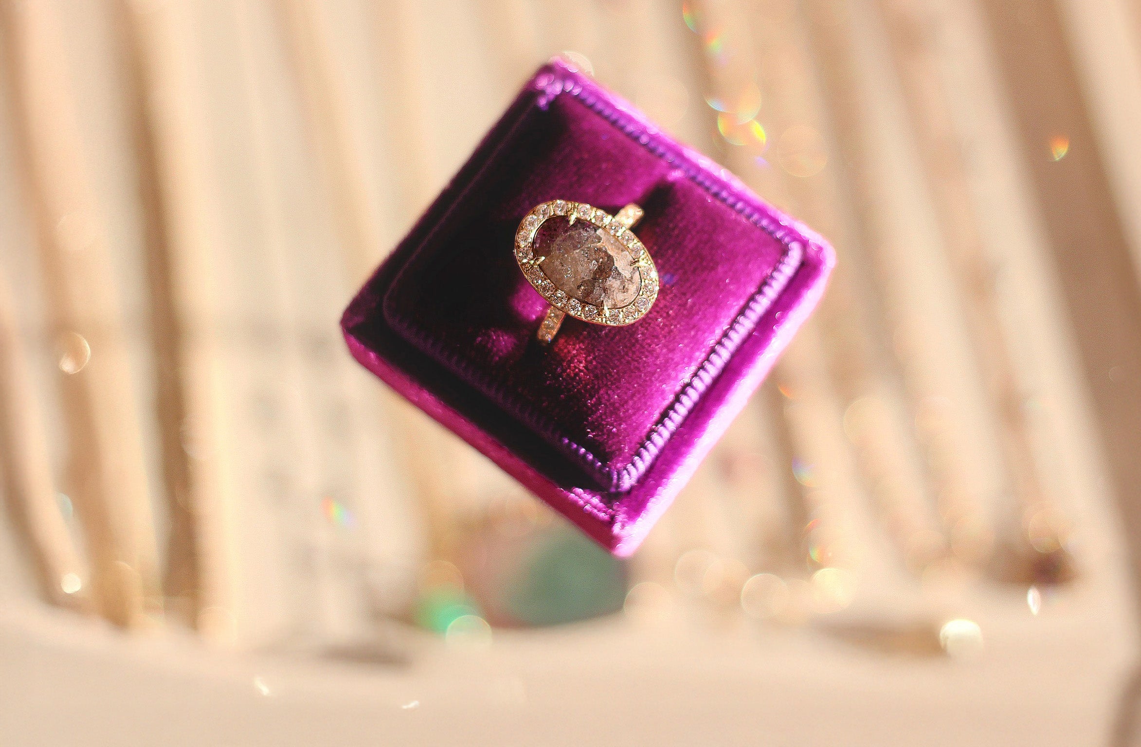 Gold ring with a large oval gemstone on a purple velvet stand against a blurred background