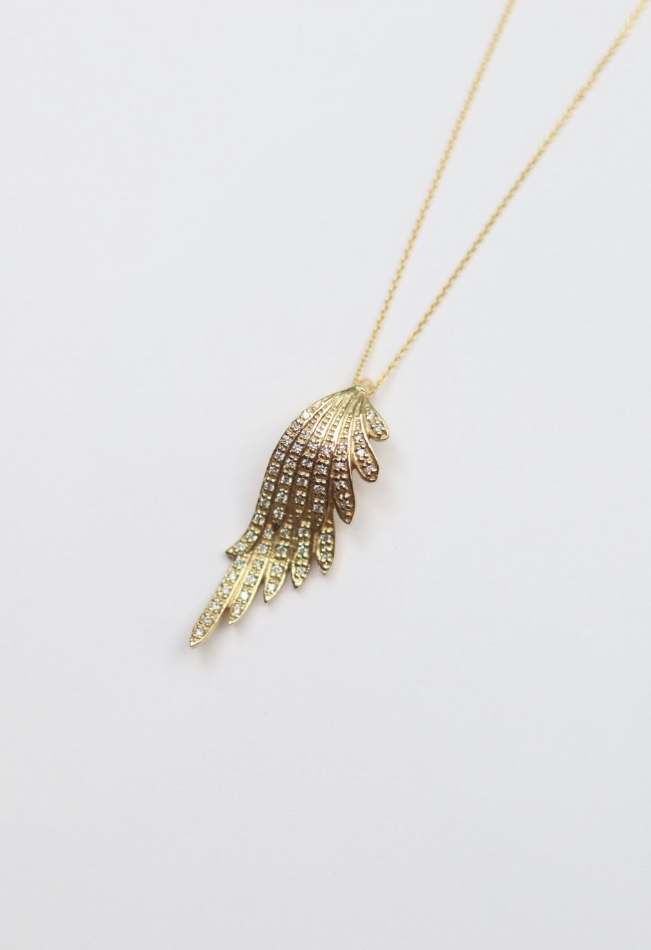Gold hand-shaped pendant necklace on a light gray background