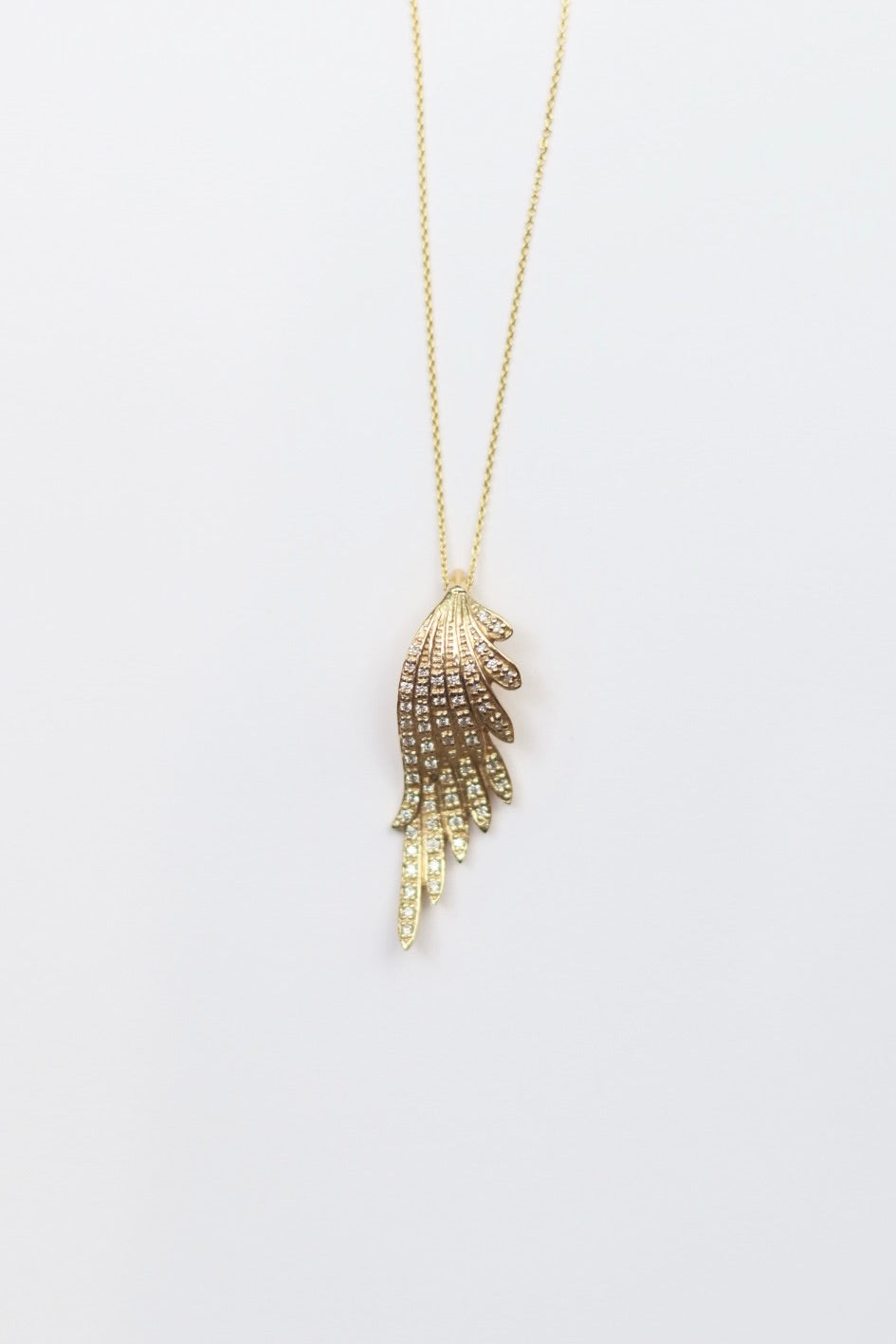 Gold feather-shaped pendant on a chain against a white background