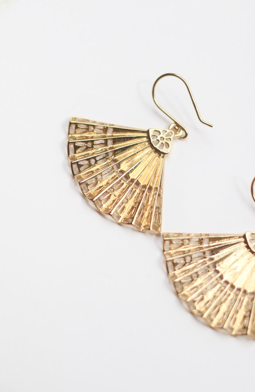 Gold fan-shaped earrings on a white background