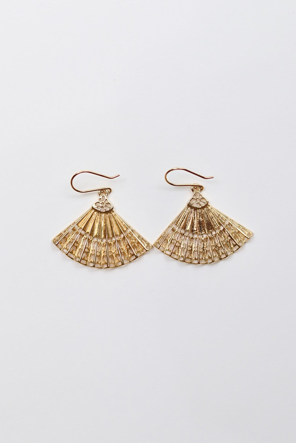 Gold fan-shaped earrings on a light gray background