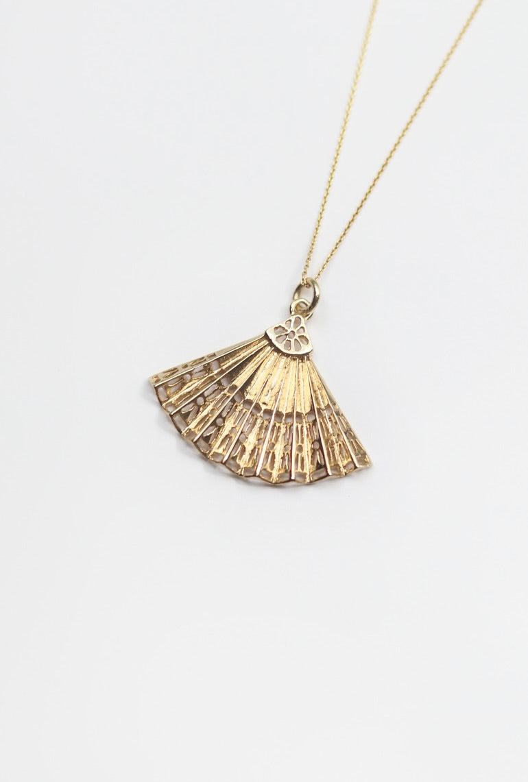Gold fan-shaped pendant necklace on a white background
