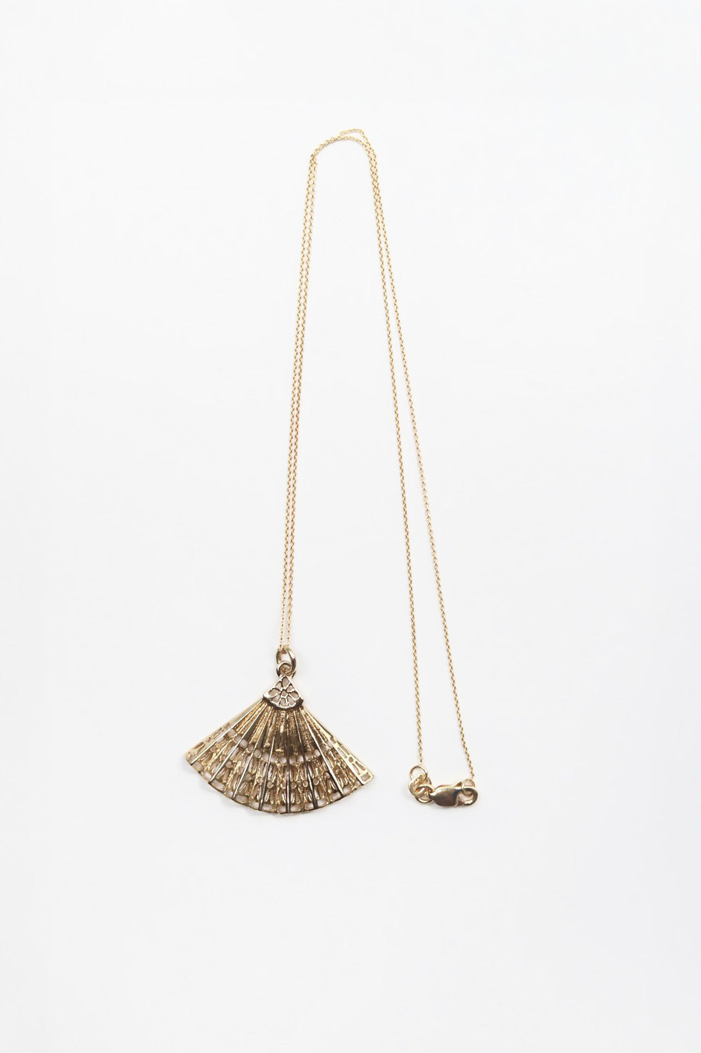 Gold necklace with a fan-shaped pendant on a white background