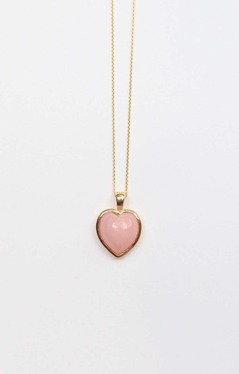 Heart-shaped pink pendant on a gold chain against a white background