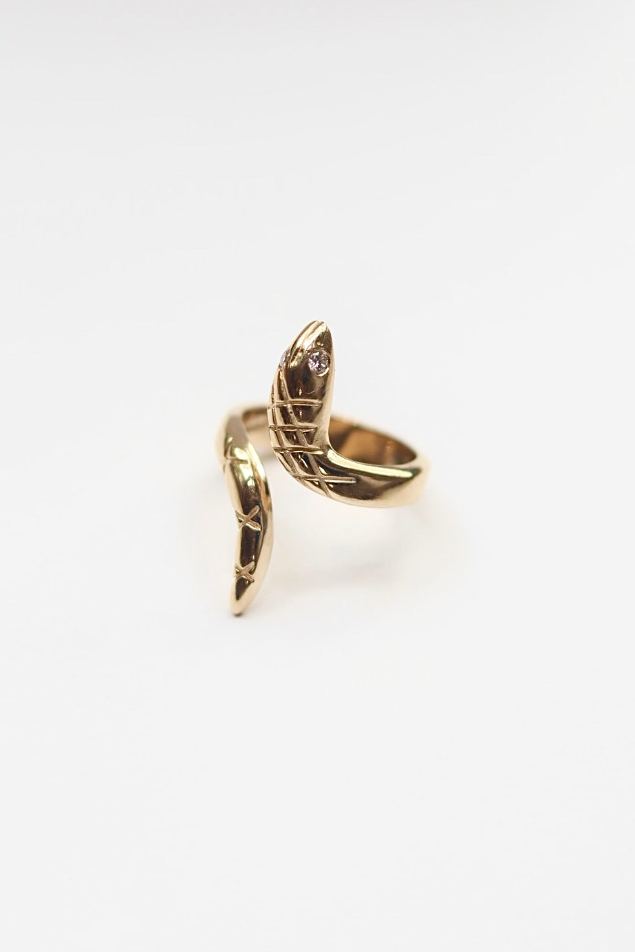 Gold snake ring  with diamond eyes on a white background