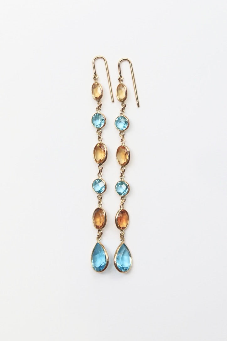 Pair of earrings with blue and gold stones on a white background
