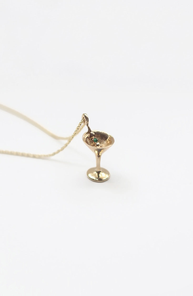 Gold martini necklace on a white background
