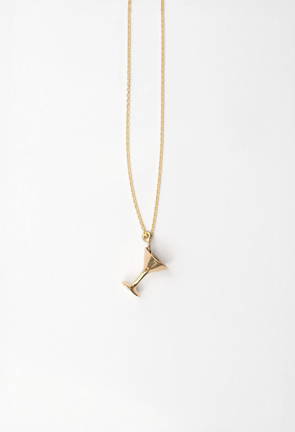 Gold necklace with a martini glass pendant on a white background