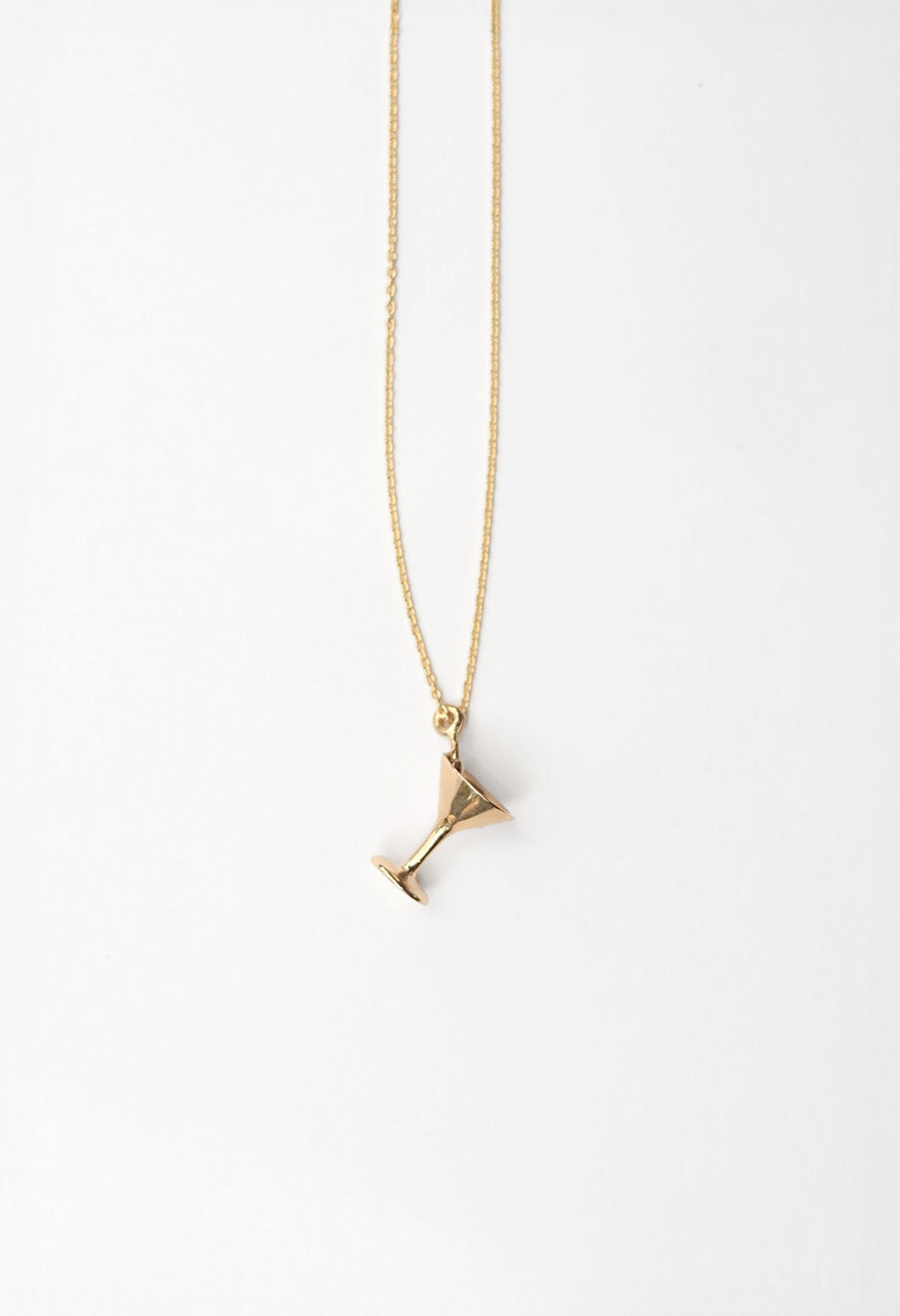 Gold necklace with a martini glass pendant on a white background