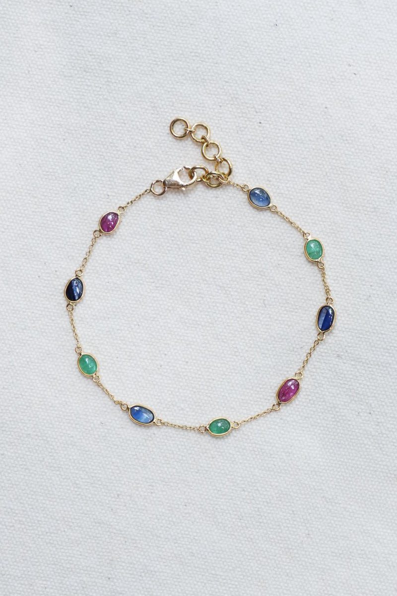 Gold bracelet with multicolored gemstones on a light gray background
