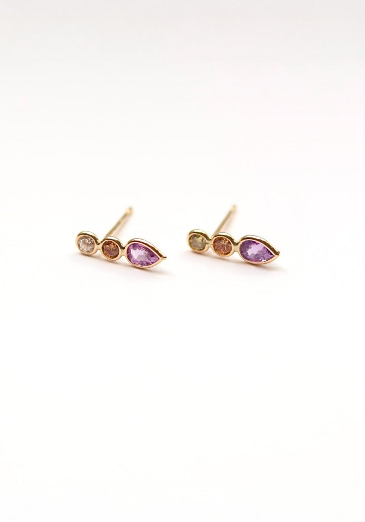 Pair of gold earrings with pink gemstones on a white background