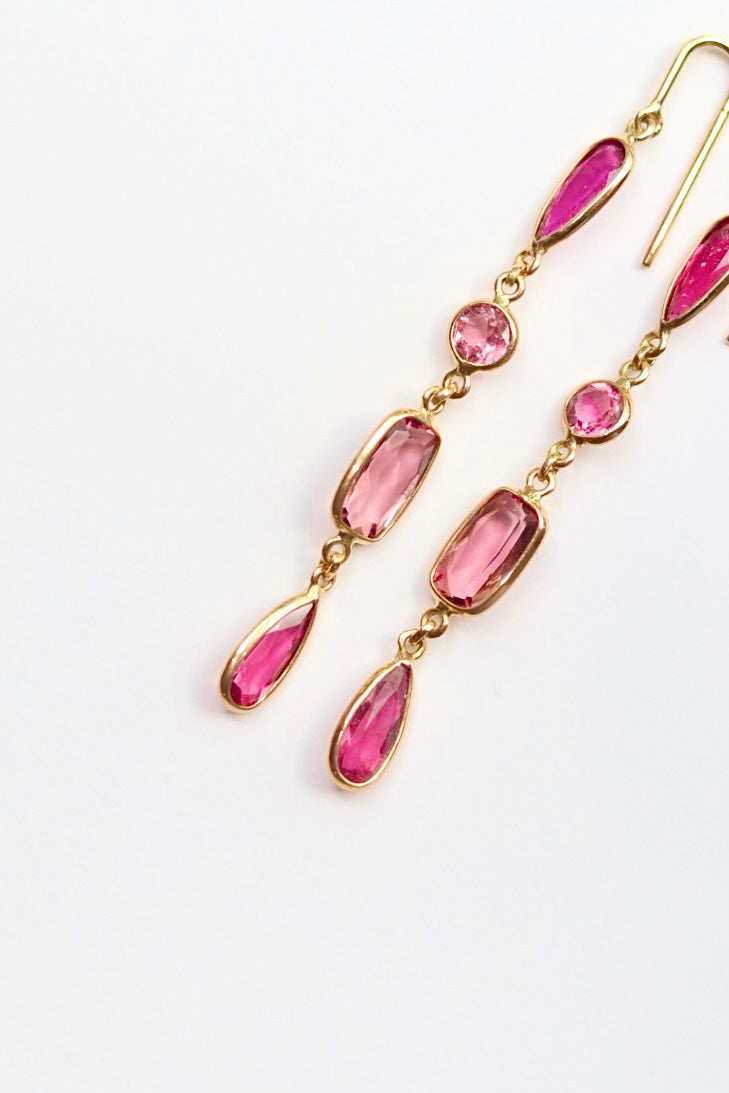 Gold earrings with pink gemstones on a white background