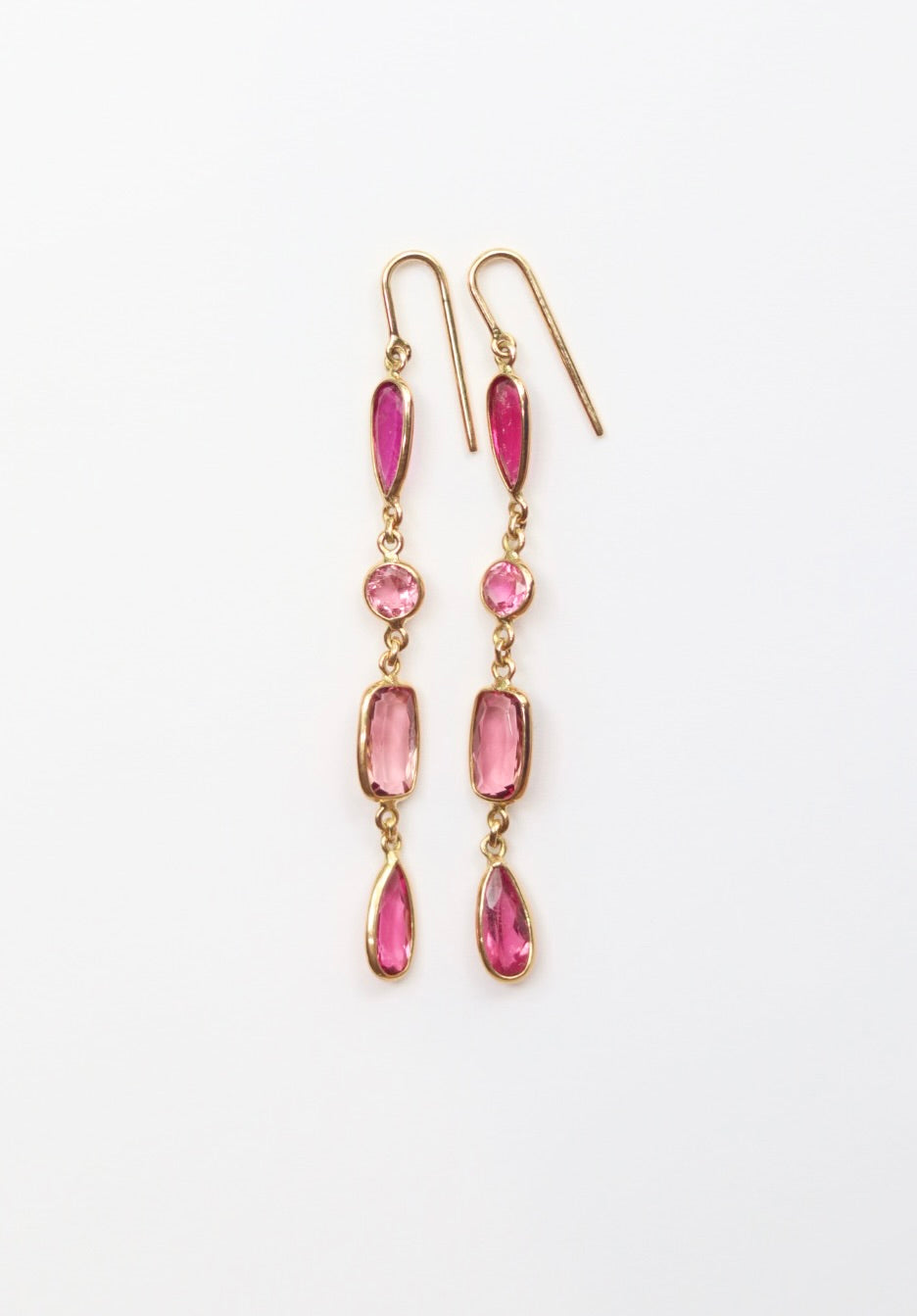 Gold earrings with pink gemstones on a white background