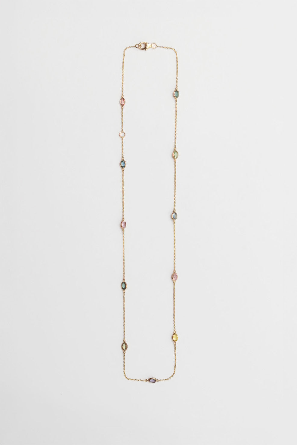 Long necklace with multicolored gemstones on a light gray background