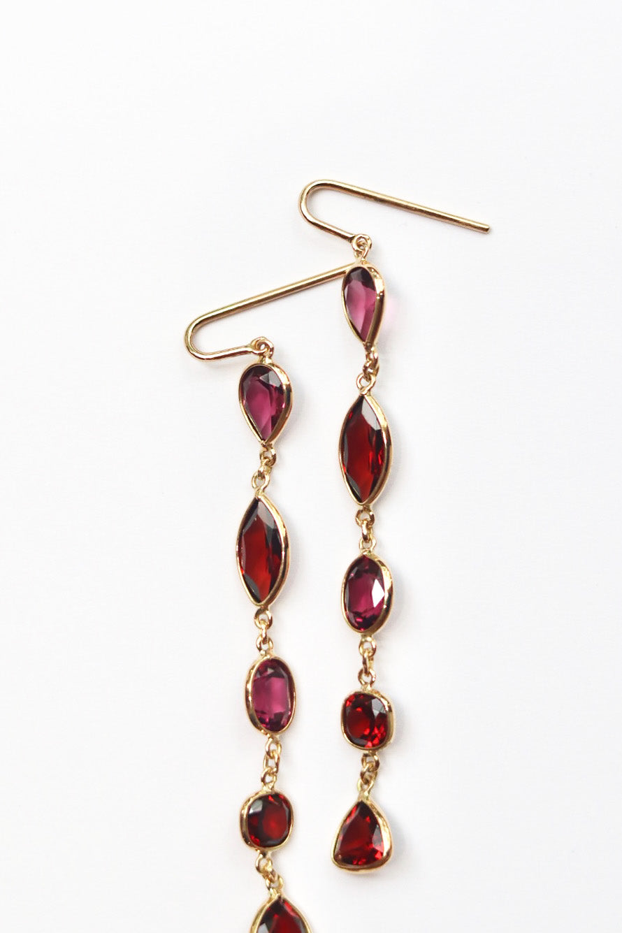Gold earrings with red gemstones on a white background