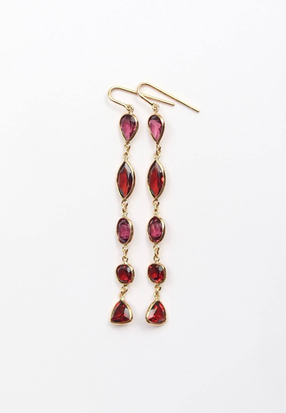 Gold earrings with red gemstones on a white background