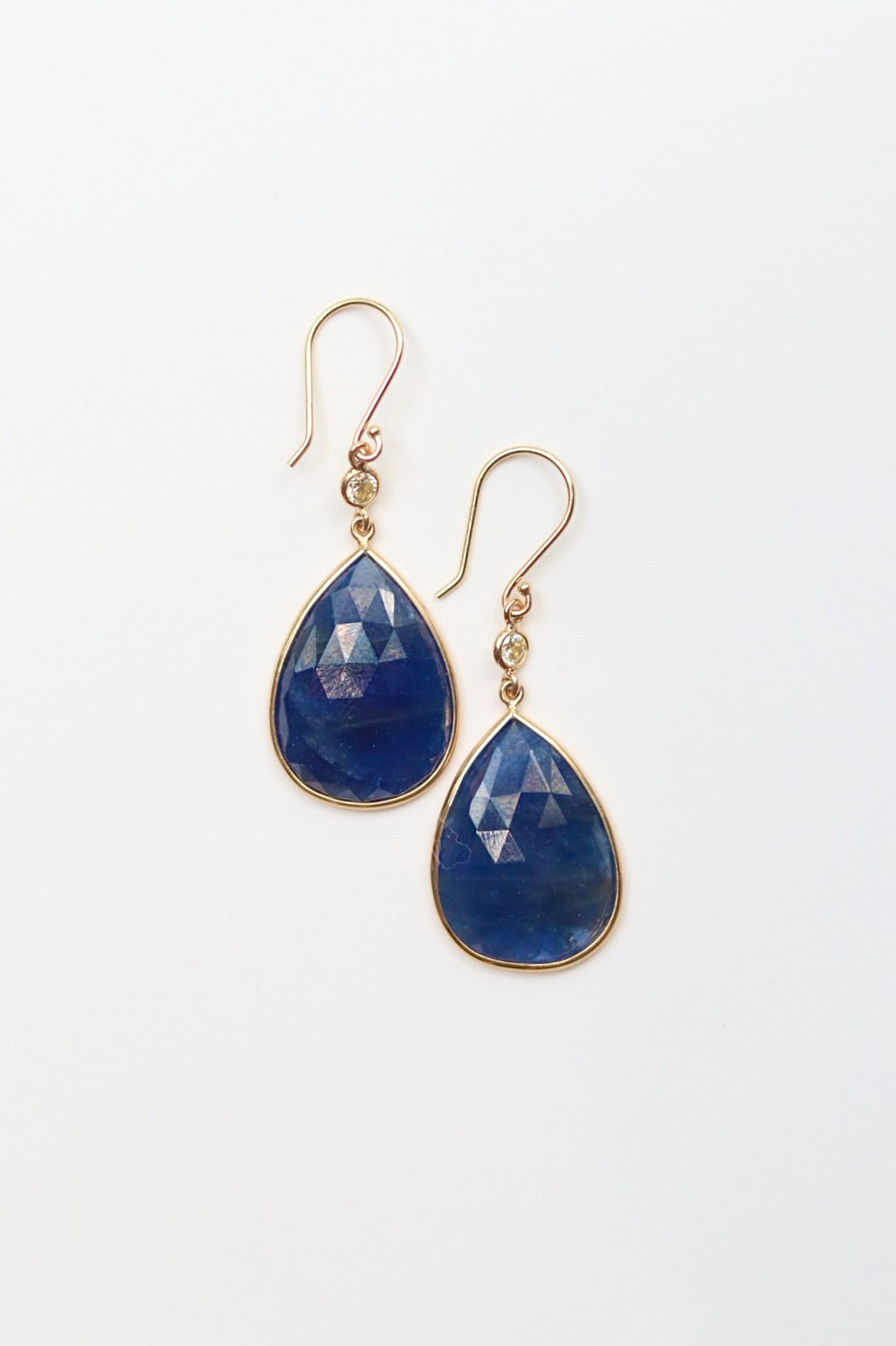 Gold earrings with blue teardrop-shaped stones on a white background