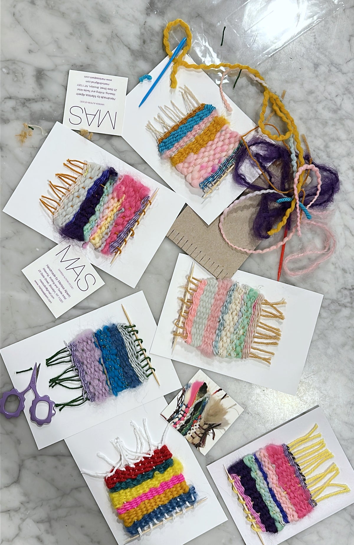 Colorful woven hair accessories on a marble surface with 'MAS' branding.