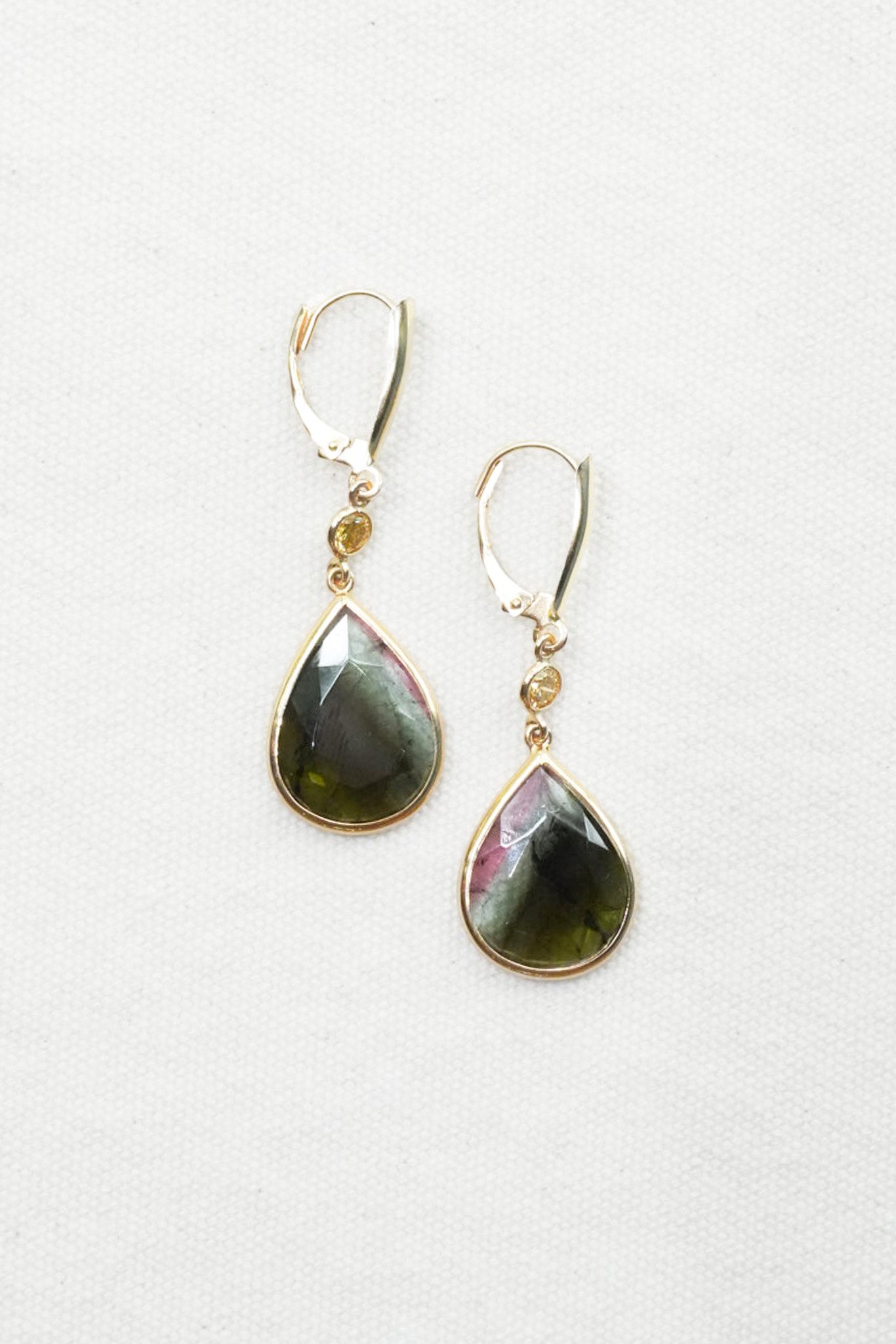 Gold earrings with diamond-like stones on a white background