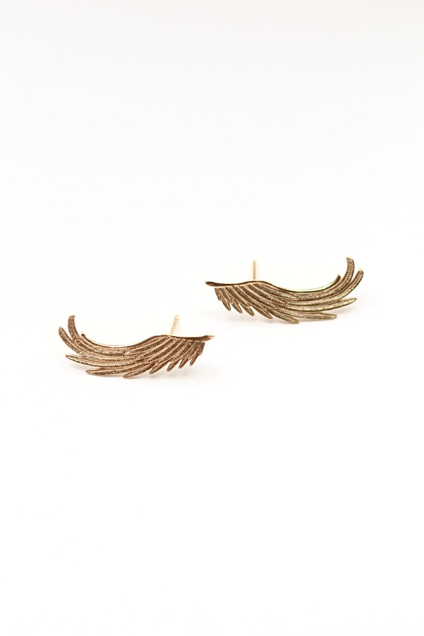 Pair of gold wing-shaped earrings on a white background