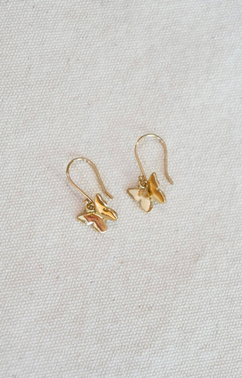 Pair of gold butterfly earrings on a light gray background