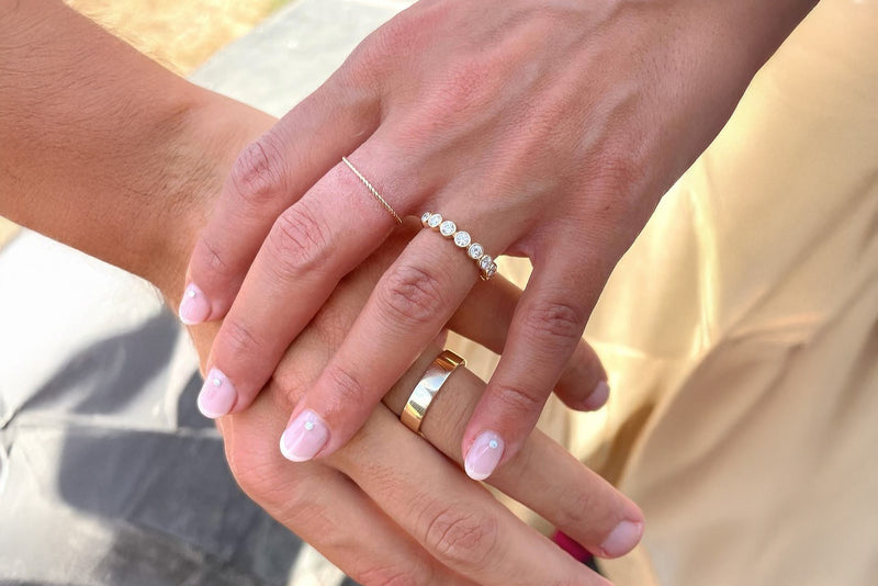 Close-up of two hands holding each other, wearing rings.