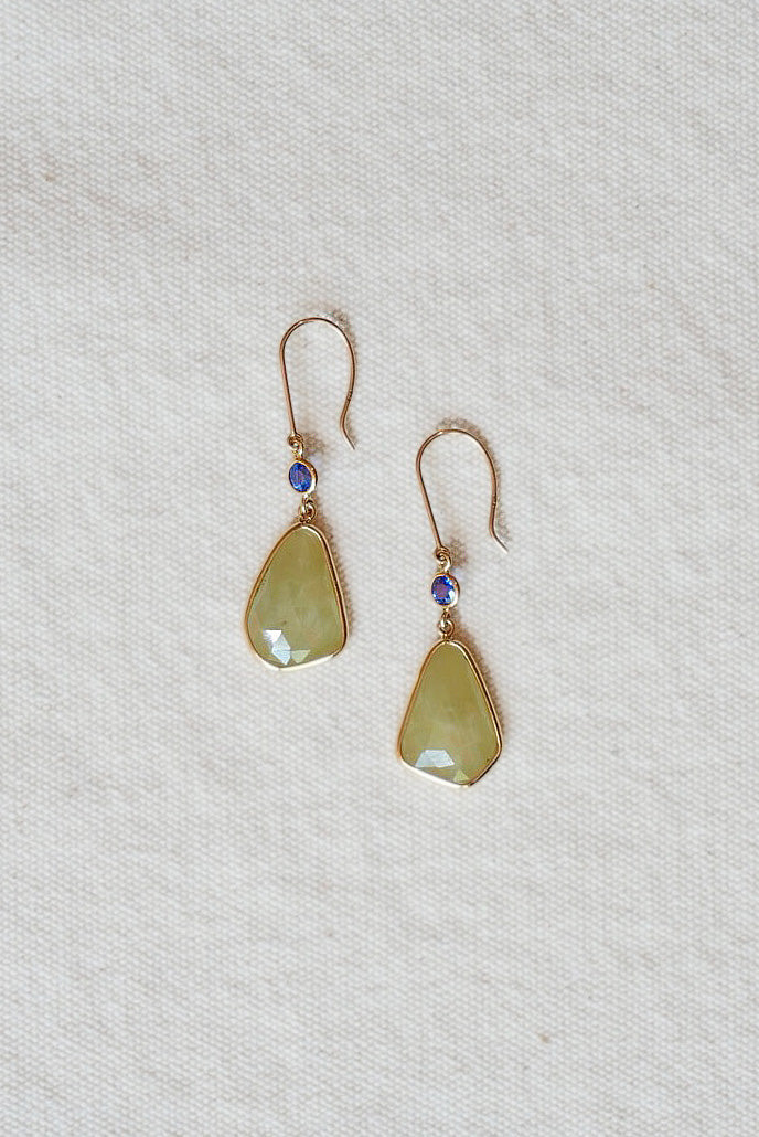 Pair of gold earrings with green teardrop-shaped stones on a light gray background