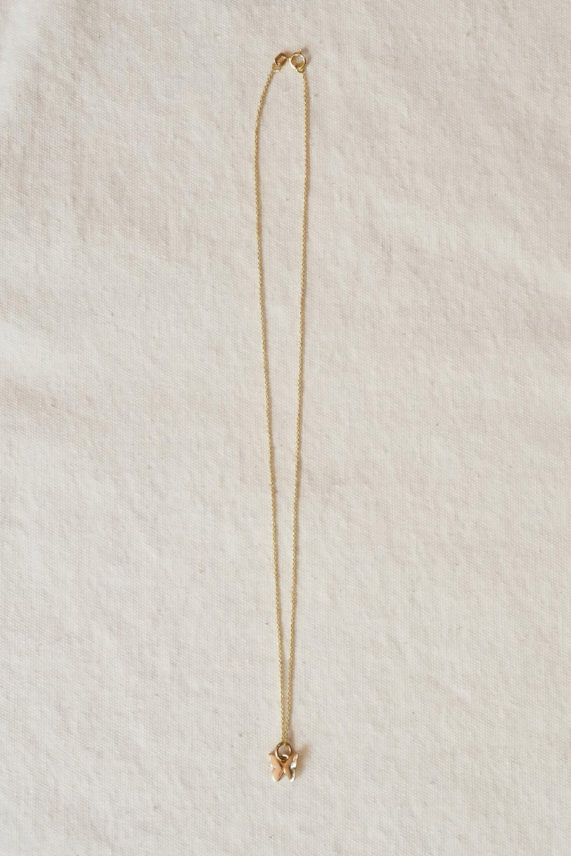 Gold necklace on a textured beige surface