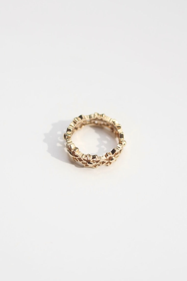 Gold flower ring with a textured band on a white background