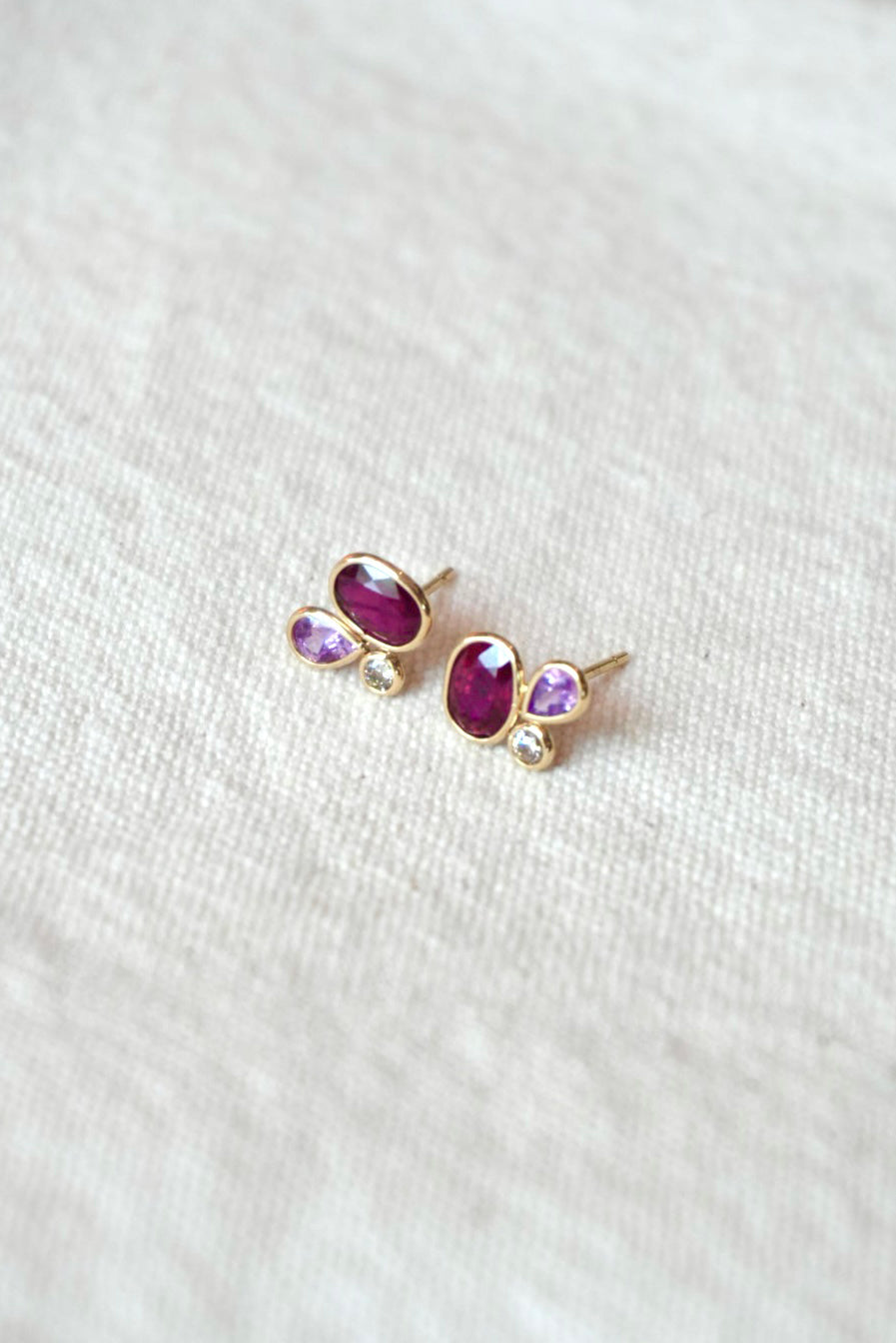 Gold stud earrings with purple and diamond gemstones on a white background