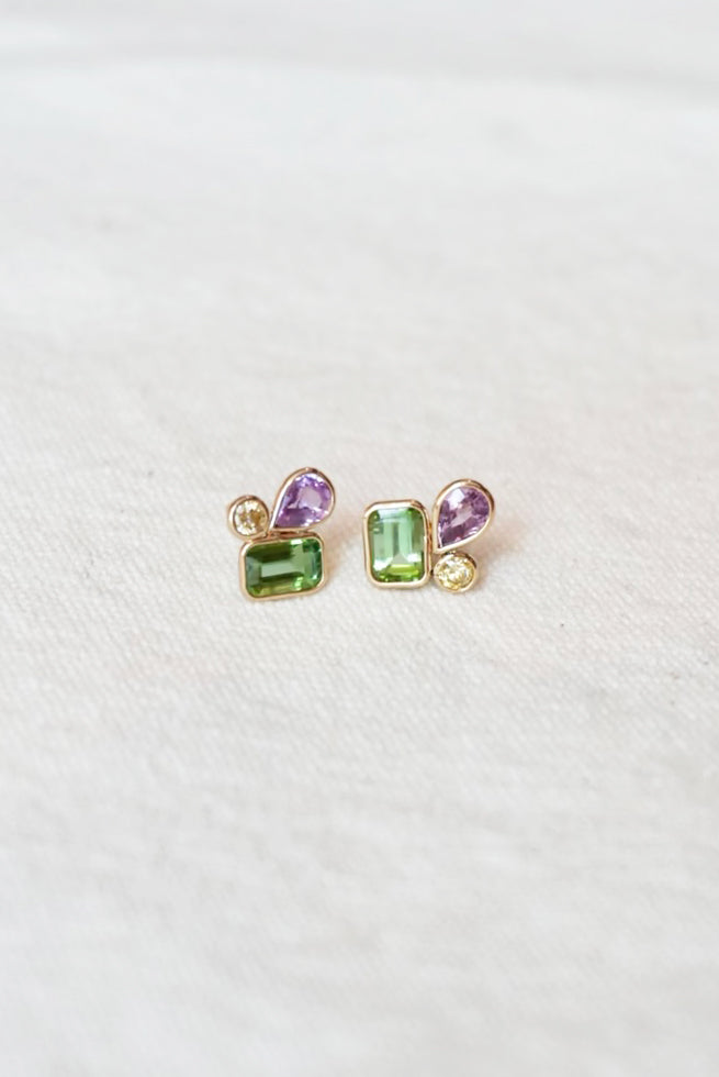Pair of gold stud earrings with green and purple gemstones on a white background
