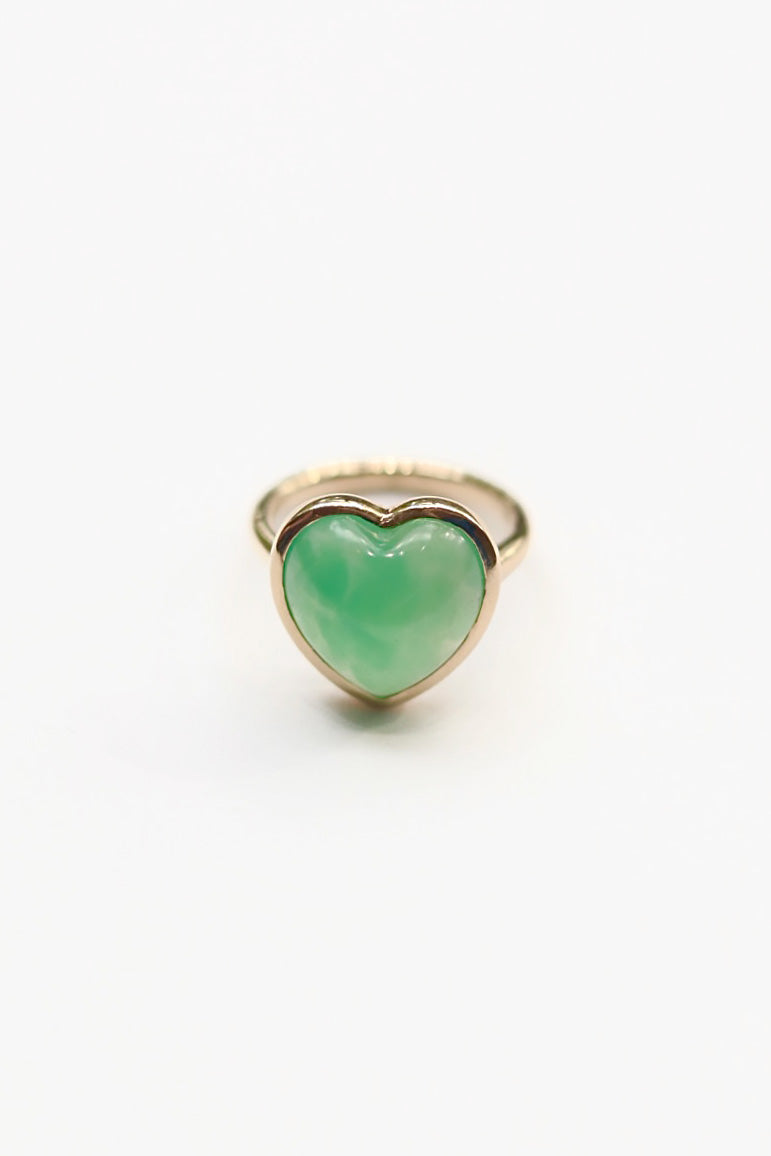 Heart-shaped green gemstone ring with gold band on a white background