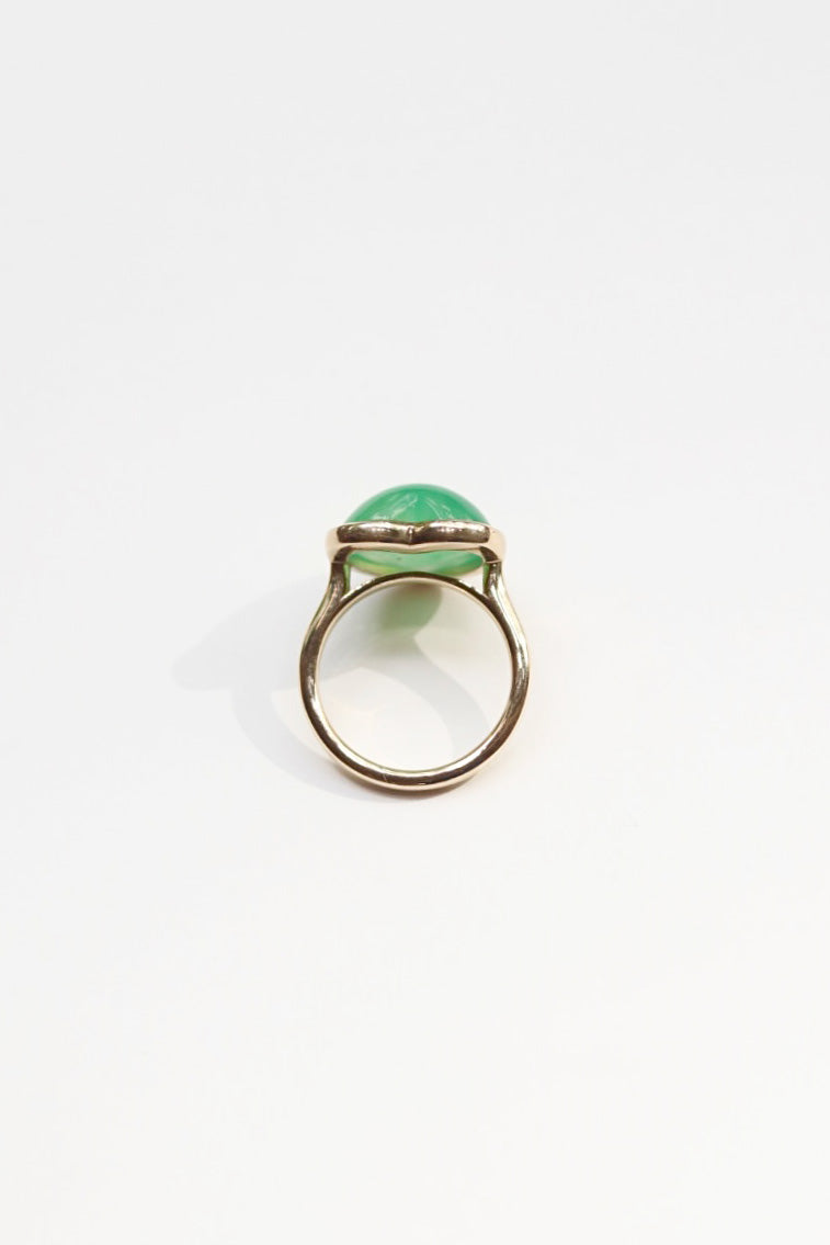 Gold ring with a green gemstone on a white background