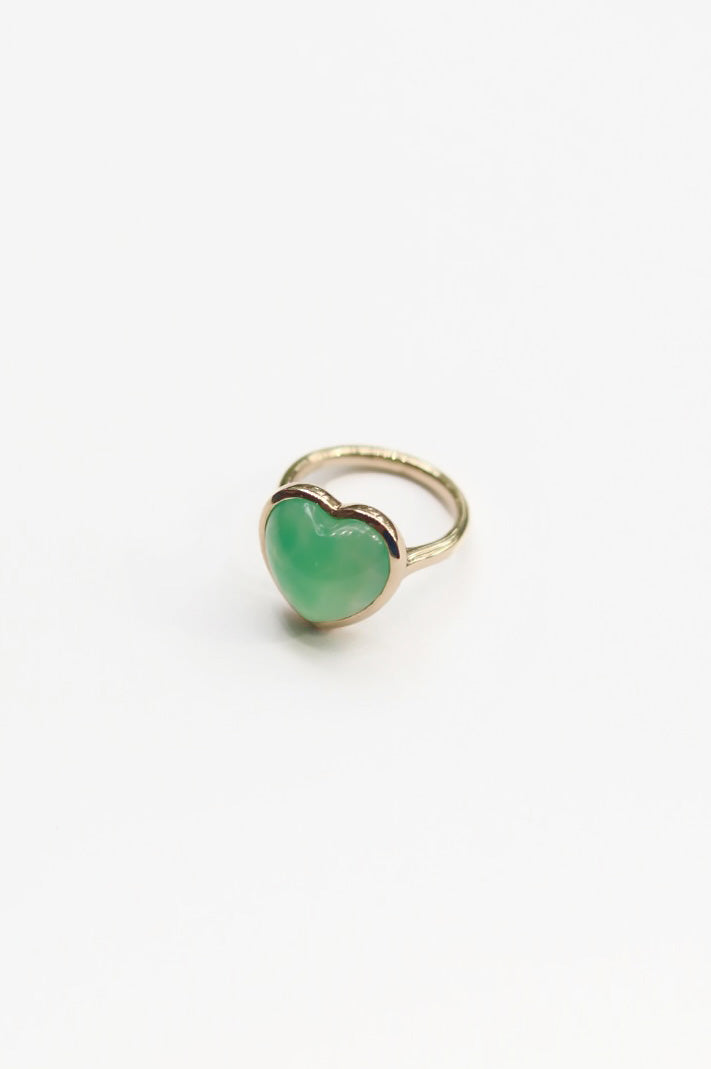 Gold ring with a green heart-shaped gemstone on a white background
