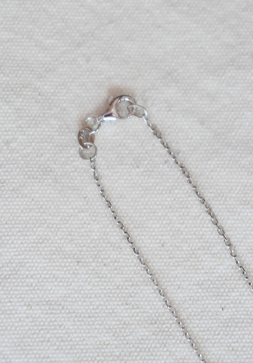 Close-up of a silver chain on a light gray fabric background