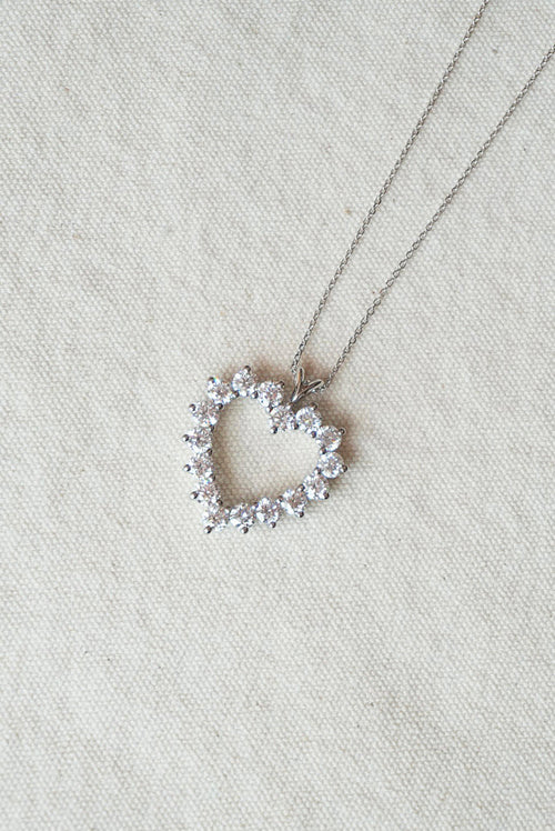 Heart-shaped necklace with small diamonds on a light cream fabric background