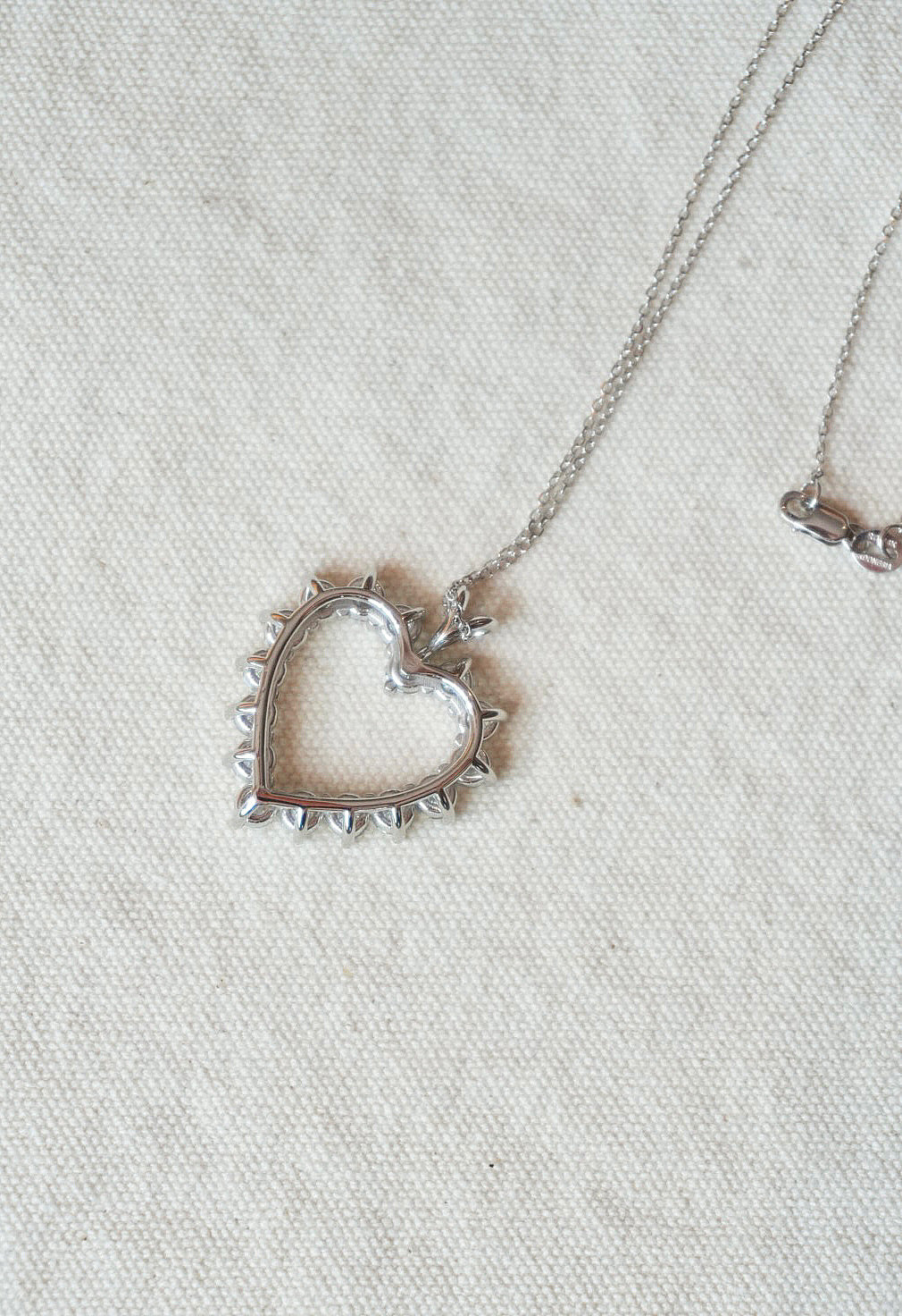 Silver heart-shaped pendant necklace on a light fabric background