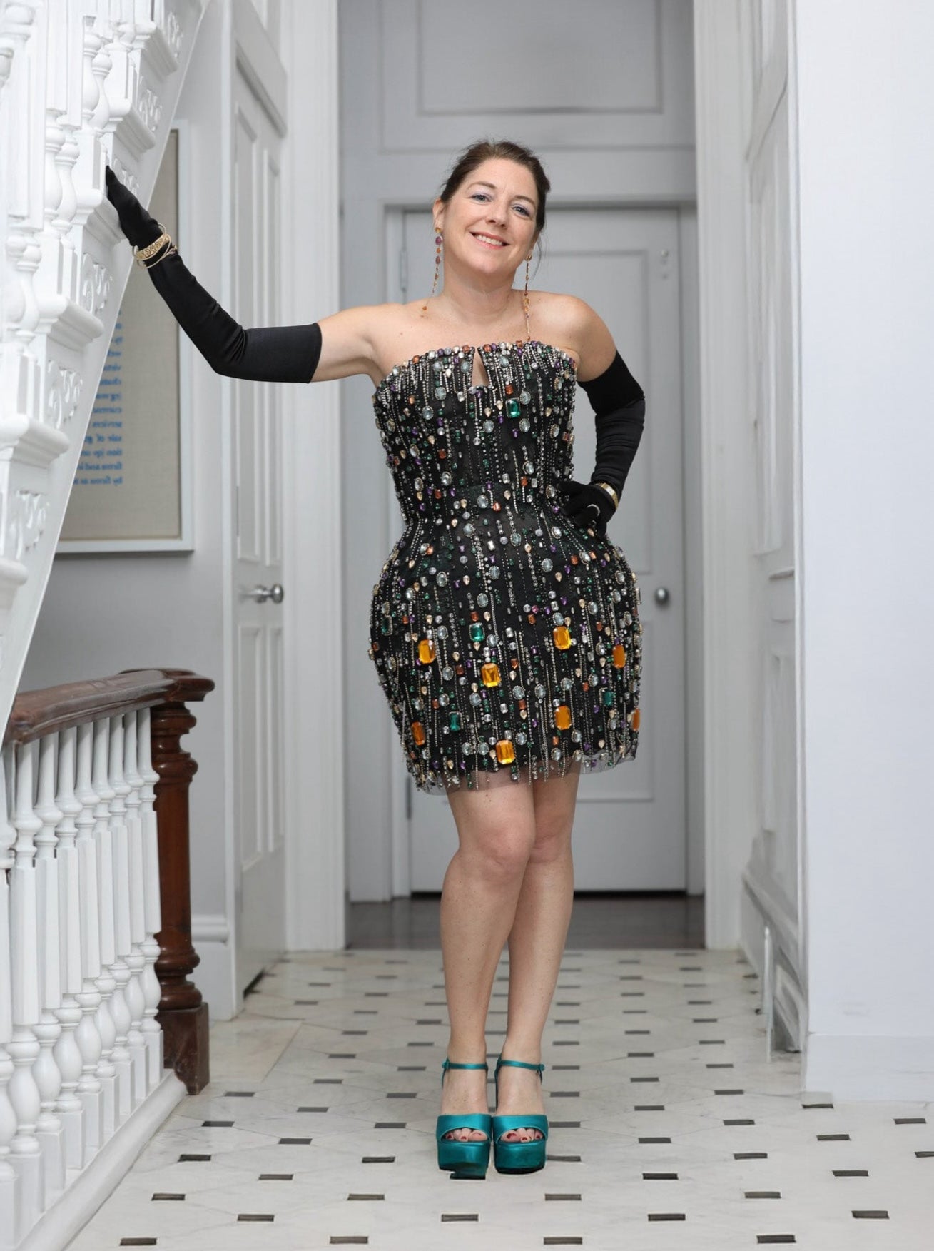 Woman in a strapless gemstone dress with decorative elements standing in a hallway.