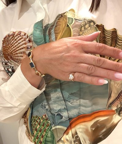 Hand with a colorful gemstone bracelet and heart diamond ring.